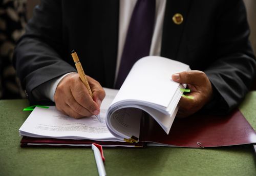 Az aláíró könyv látszik, csak a könyv és a kezek látszanak, a jobb kéz éppen aláír benne