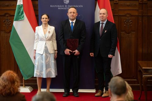 Orgoványi József áll középen, oklevéllel a kezében, jobbján egy nő, balján a Pálmai Gergely, két oldalt pedig magyar zászlók