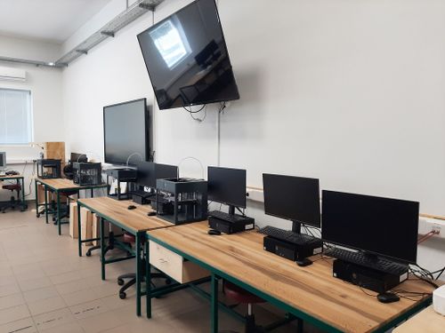 A DKA számítógépes tanterme, számítógépek az asztalokon,nagyméretű tv a falon, digitális tábla a háttérben