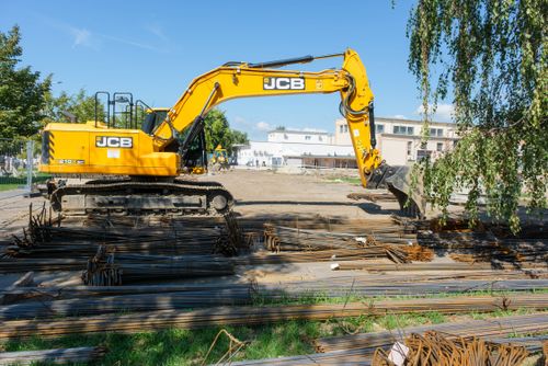VSZC alapkőletétel: Markolkógép a lebontott területen, körülötte betonvasak a háttérben a DKA