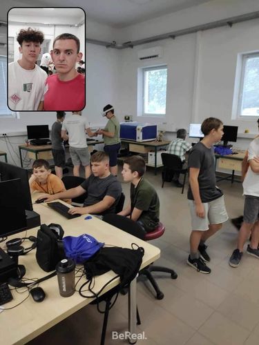 Tanulók a DKA (digitális közösségi alkotótér) termében számítógép előtt ülnek, programoznak valamit, a háttérben pedig három tanuló a VR szemüveget próbálja