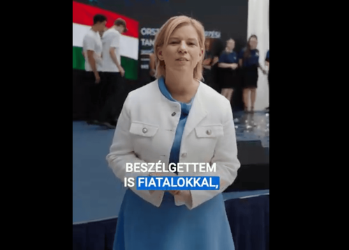 Varga-bajusz Veronika államtiták asszony videójának képe, a képviselőnő áll rajta, mögötte magyar zászló és fiatalok, felirat: "beszélgettem is fiatalokkal,"